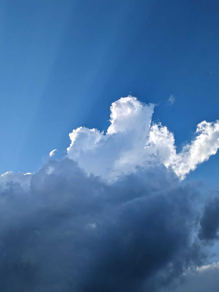 Sunbeams emerge from behind a large, dramatic cloud.