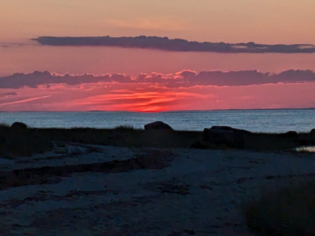 Fiery red sunset over a calm ocean and beach.