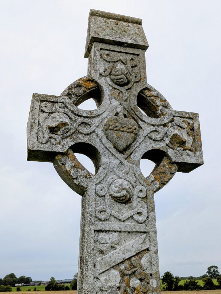 Intricately carved stone Celtic cross with Sacred Heart detail.